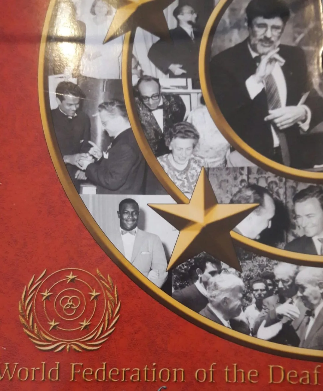 Capa vermelha de publicação da World Federation of the Deaf, com emblema dourado e mosaico de fotografias históricas.